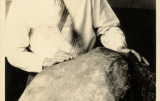 An autographed photo of a young H.H. Nininger examining a large meteorite.